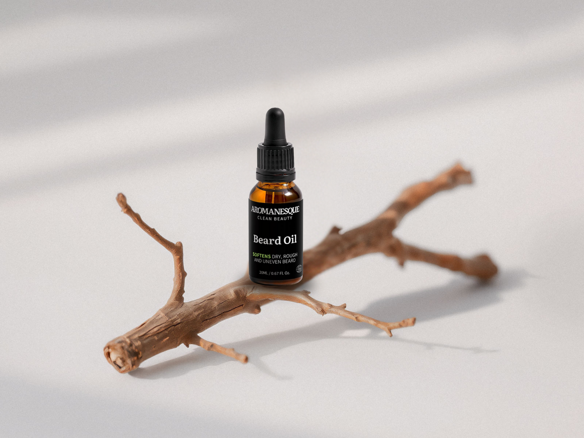 A bottle dropper of Aromanesque beard oil on a branch with a neutral background